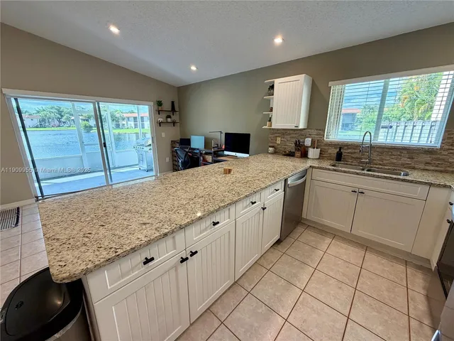 a large kitchen with granite countertop counter space a sink a window and stainless steel appliances