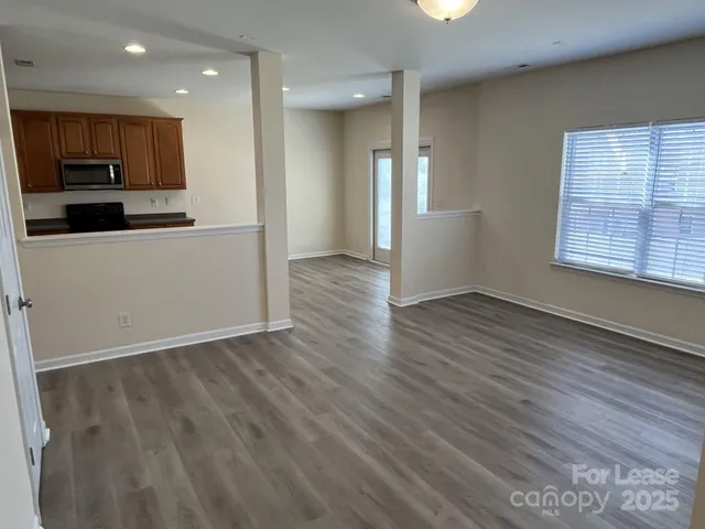 an empty room with wooden floor and a kitchen