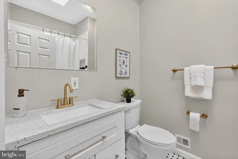 a bathroom with a granite countertop toilet sink and mirror