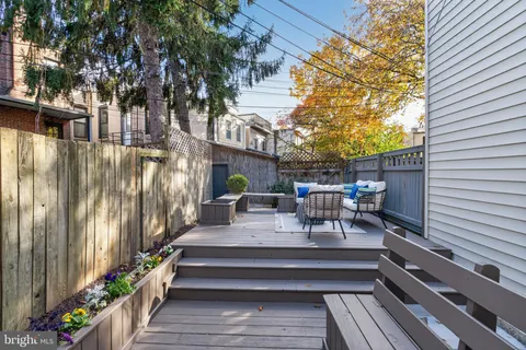 a view of a patio with couches table and chairs with wooden fence and plants