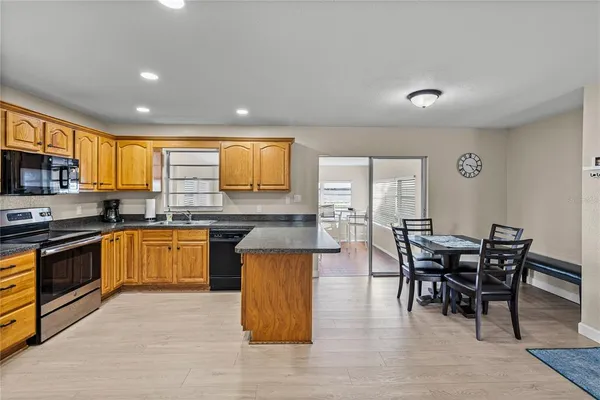 a kitchen with stainless steel appliances granite countertop wooden floor a dining table and chairs