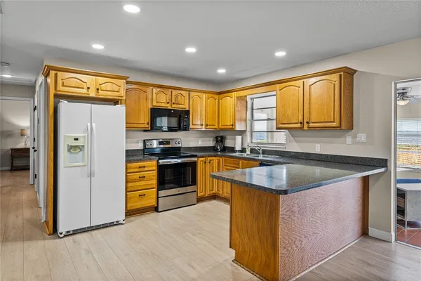 a kitchen with stainless steel appliances granite countertop sink stove top oven and refrigerator