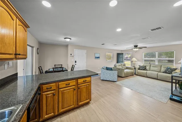 a large kitchen with stainless steel appliances granite countertop a lot of cabinets wooden floor and a couch