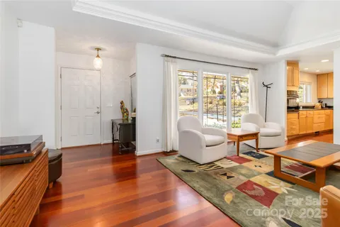 a living room with furniture a wooden floor and next to a window