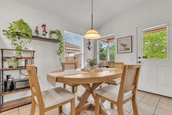 a kitchen with stainless steel appliances granite countertop a refrigerator a stove a sink a dining table and chairs with wooden floor