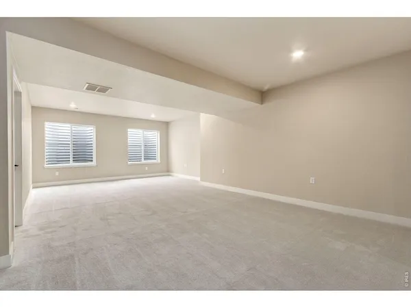 a view of an empty room with a kitchen and a window