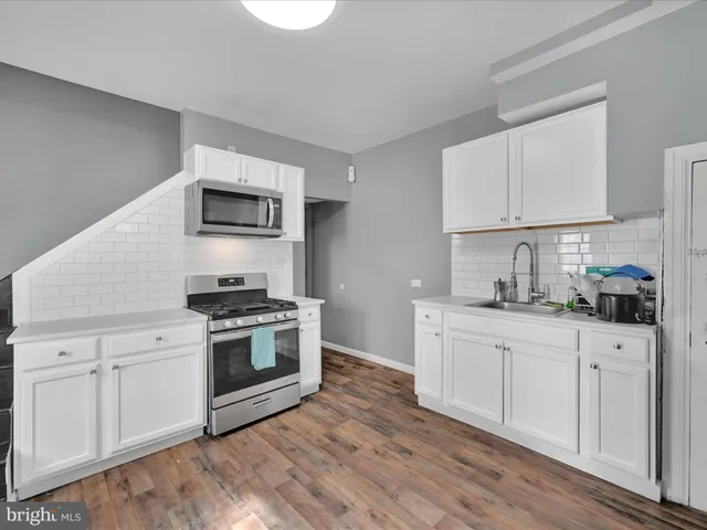 a kitchen with cabinets stainless steel appliances and wooden floor