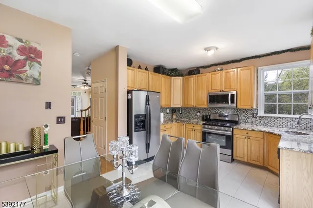 a kitchen with stainless steel appliances granite countertop a refrigerator a stove a sink a dining table and chairs with wooden floor