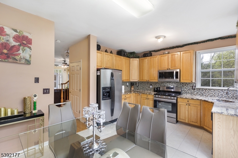 3 Keats Court Hightstown, NJ 08520 - Photo 5 of 7 a kitchen with stainless steel appliances granite countertop a refrigerator a stove a sink a dining table and chairs with wooden floor