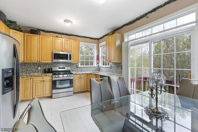 a kitchen with stainless steel appliances granite countertop a stove top oven a sink a dining table and chairs