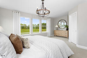 6308 Little Drew Lane Raleigh, NC 27610 - Photo 7 of 9 a bedroom with a bed a chandelier and a large window