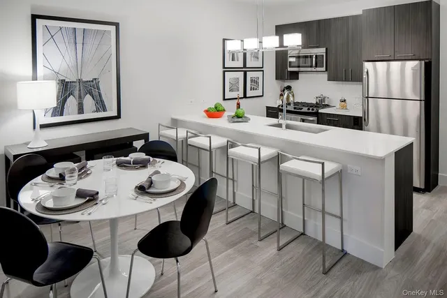 a kitchen with stainless steel appliances granite countertop a sink a stove a dining table and chairs