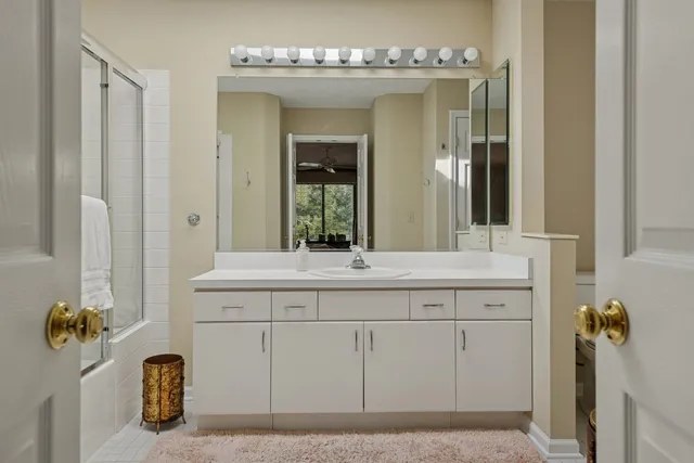 a bathroom with a shower sink vanity and mirror