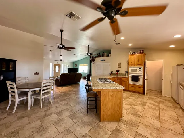 a kitchen with stainless steel appliances kitchen island granite countertop a table chairs and a refrigerator