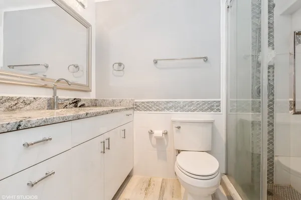 a bathroom with a granite countertop toilet sink and mirror