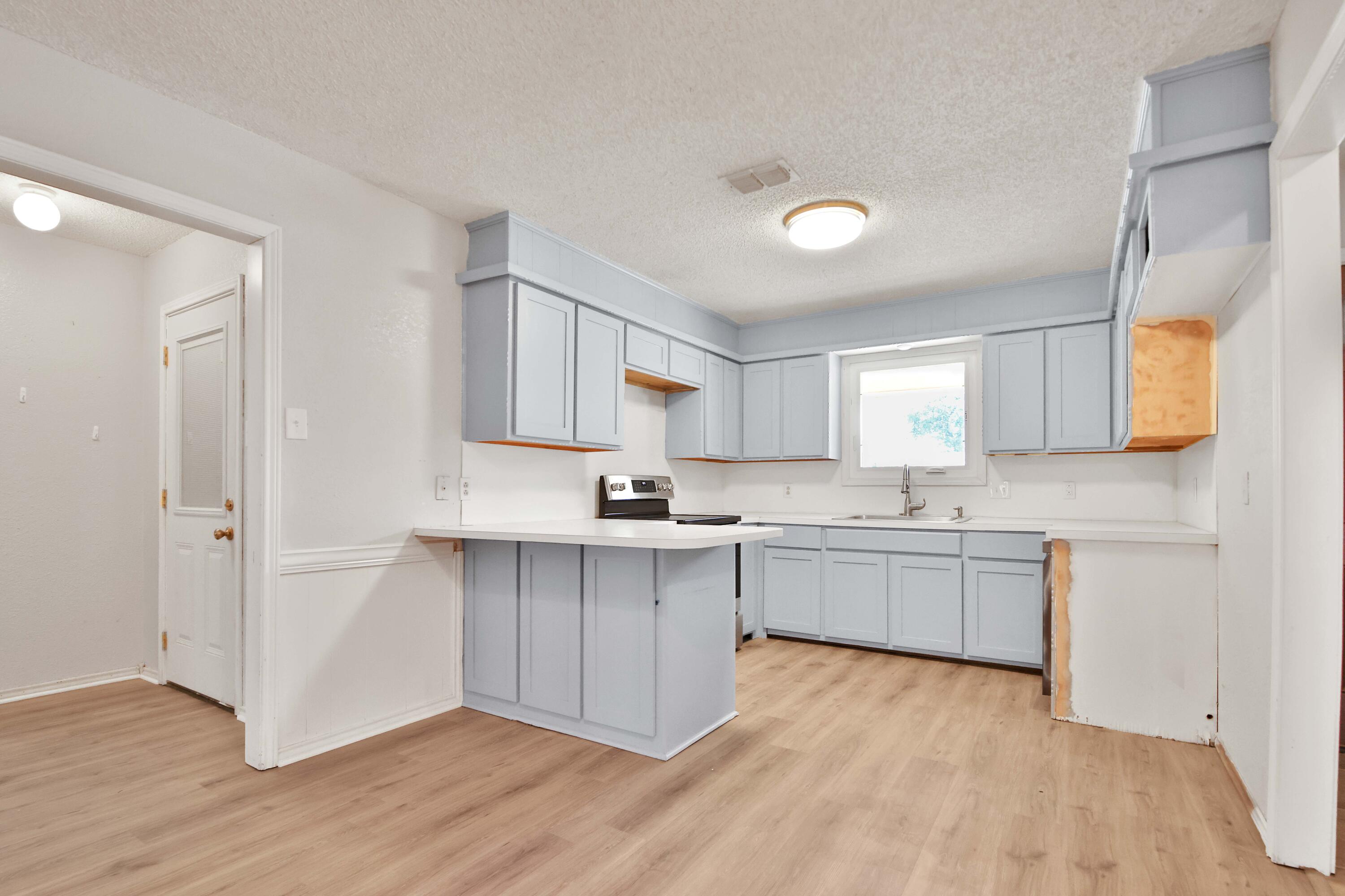 4818 73rd Street Lubbock, TX 79424 - Photo 6 of 31 a kitchen with a sink cabinets and wooden floor