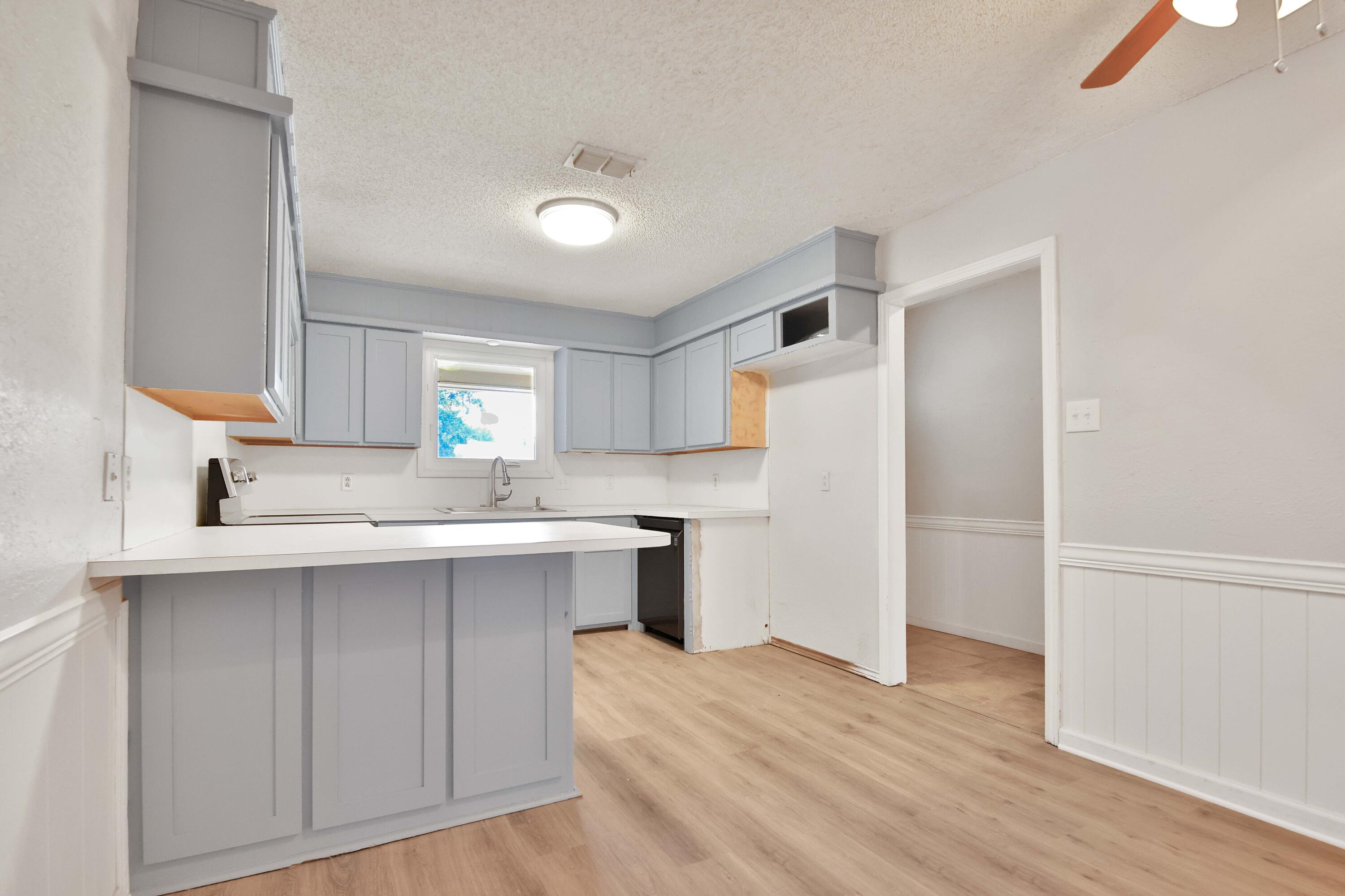 4818 73rd Street Lubbock, TX 79424 - Photo 7 of 31 a kitchen with a sink a window a refrigerator and wooden floor