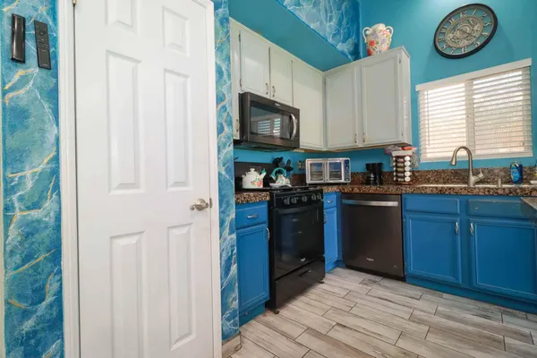 a kitchen with stainless steel appliances granite countertop a refrigerator a sink dishwasher a dining table and chairs with wooden floor