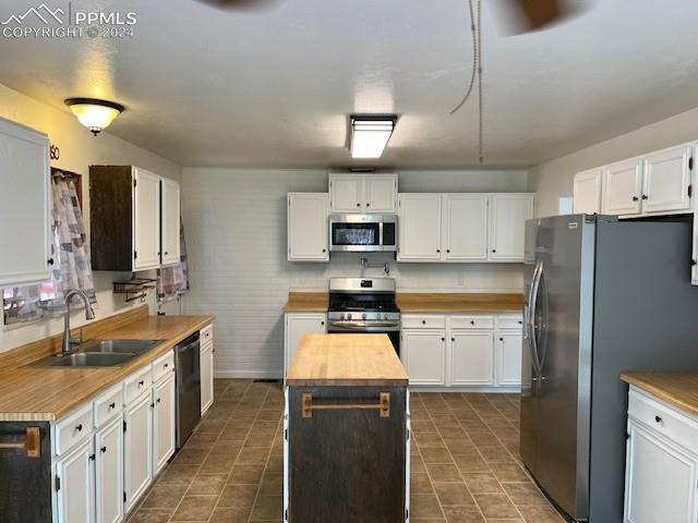 7280 Mathews Road Colorado Springs, CO 80908 - Photo 9 of 31 Kitchen with a kitchen island, white cabinetry, sink, dark tile patterned floors, and stainless steel appliances