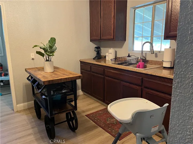 a room with a chair a dining table and a sink with wooden floor