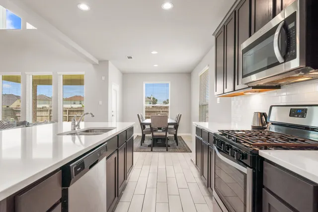 a kitchen with stainless steel appliances granite countertop a stove a sink and a microwave