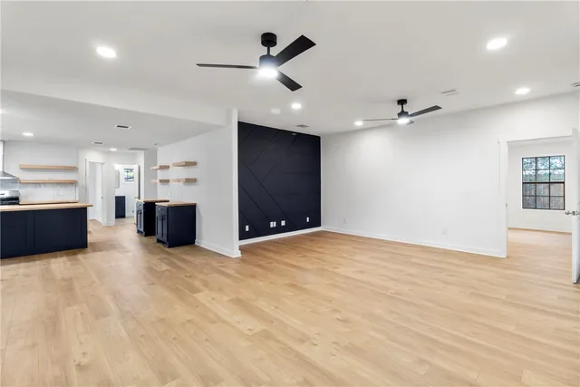 a view of an empty room with kitchen and a window