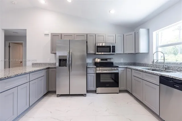 a kitchen with stainless steel appliances granite countertop a stove a sink and a refrigerator
