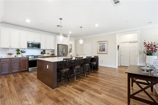 a kitchen with stainless steel appliances kitchen island granite countertop a table chairs and a refrigerator