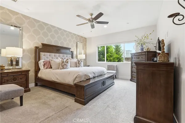 a bedroom with a large bed and a chandelier fan