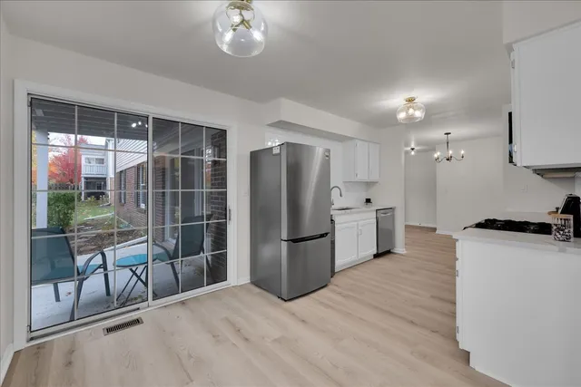 a kitchen with stainless steel appliances a refrigerator a stove a sink a dining table and chairs