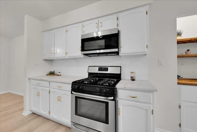 a kitchen with stainless steel appliances granite countertop grey cabinets a stove a sink and a microwave