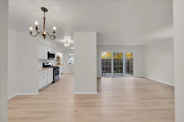 a view of an empty room with kitchen and window