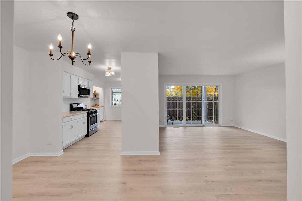 1785 Grosvenor Circle, Unit A Wheaton, IL 60189 - Photo 4 of 37 a view of an empty room with kitchen and window