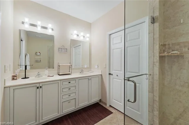 a spacious bathroom with a double vanity sink a large mirror a shower and