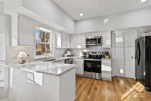 a kitchen with granite countertop a refrigerator stove top oven and sink