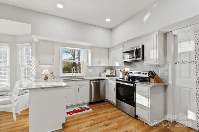 a kitchen with granite countertop stainless steel appliances a sink cabinets and a window