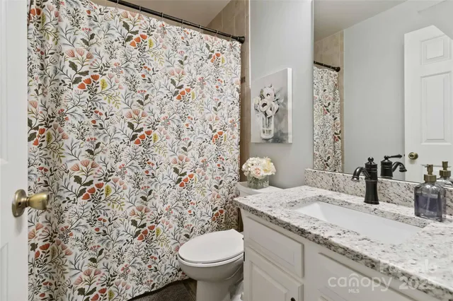 a bathroom with a granite countertop sink and a toilet