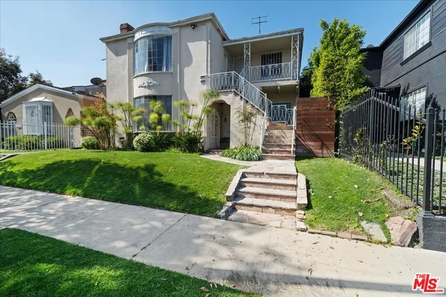 a front view of a house with a yard and potted plants