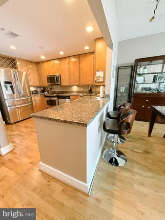 a large kitchen with stainless steel appliances kitchen island granite countertop a large kitchen counter top a stove and a sink with living room