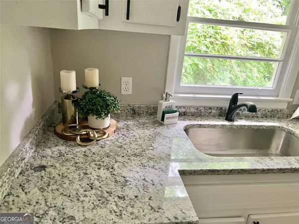 a kitchen with a granite countertop sink and a window