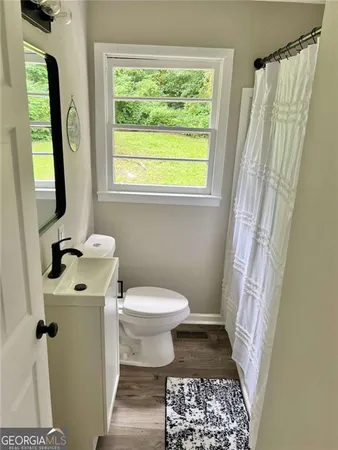 a bathroom with a sink a toilet a window and a mirror