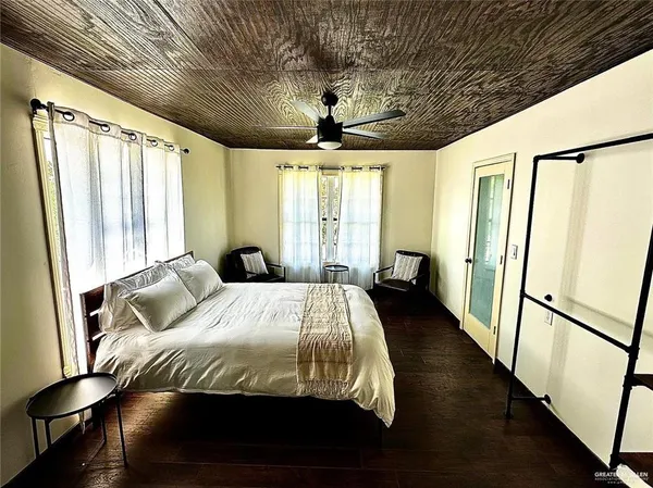 a bedroom with a bed next to a large window with wooden floor