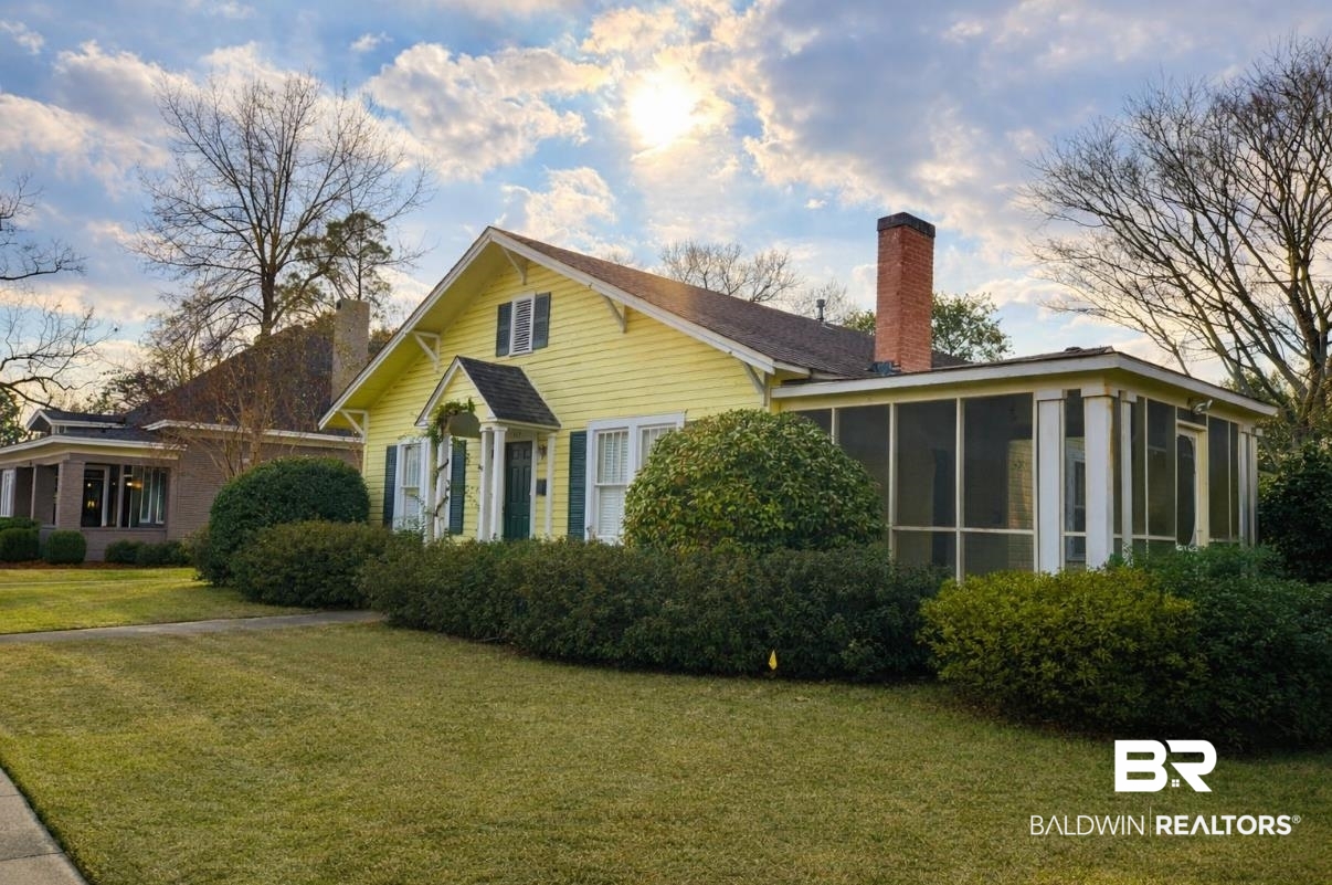 View of property exterior featuring a chimney, a lawn, and a sunroom
