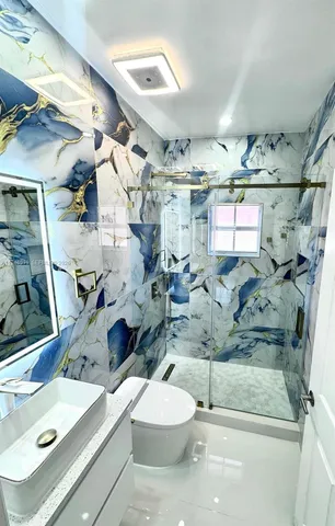 a bathroom with a sink mirror and view of living room