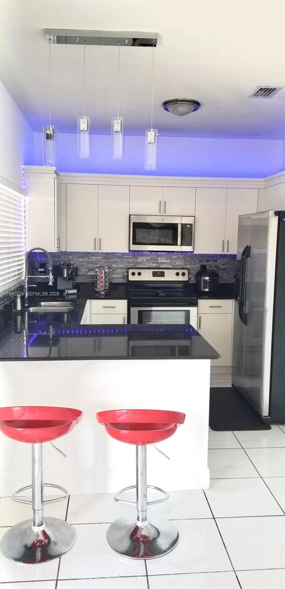 690 East 6th Place Hialeah, FL 33010 - Photo 9 of 18 a kitchen with stainless steel appliances kitchen island granite countertop a table and chairs