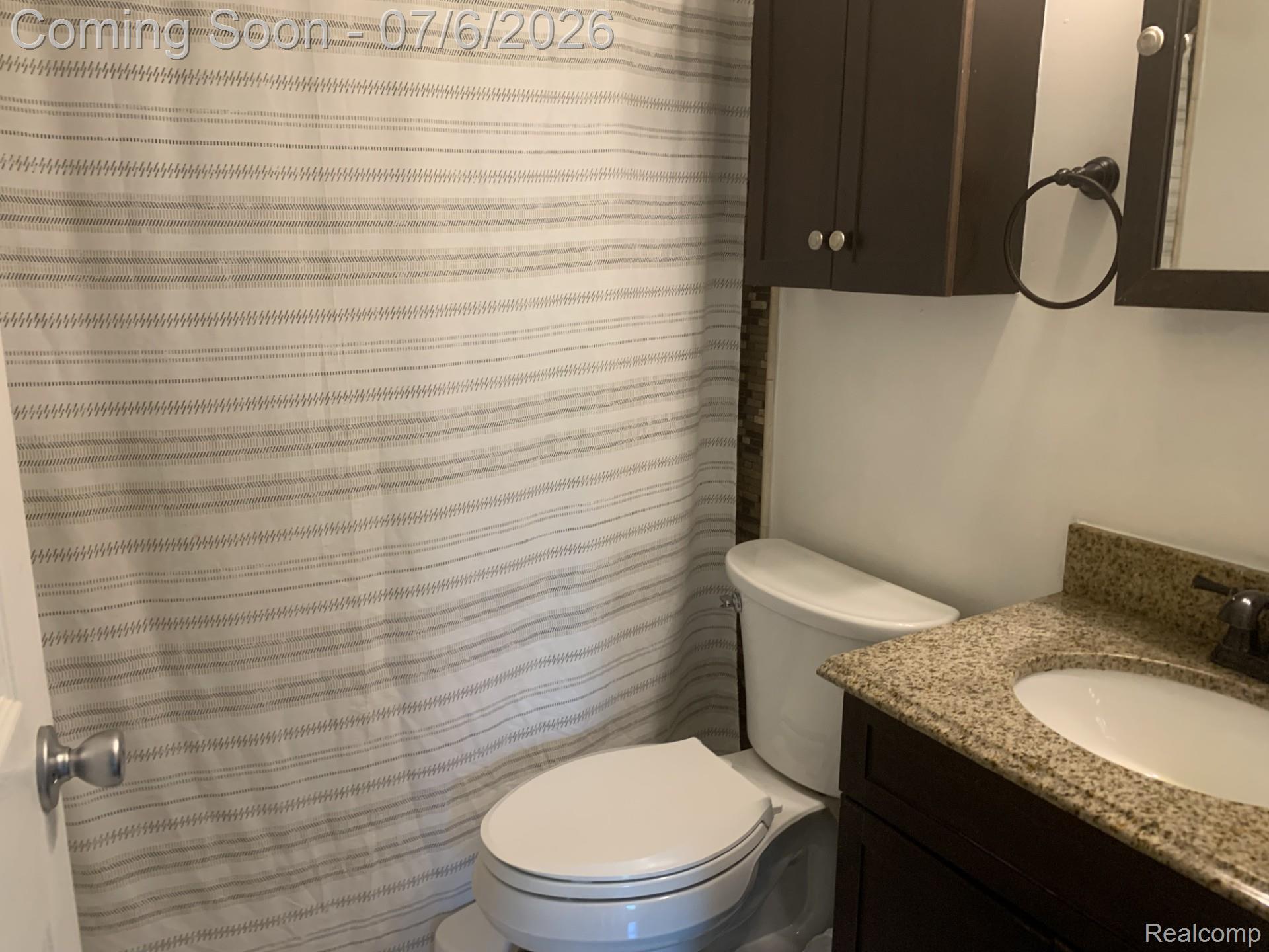 4168 Harris Road Fort Gratiot, MI 48059 - Photo 25 of 30 Bathroom vanity with a granite-finish countertop, undermount sink, and dark wood-finish cabinetry