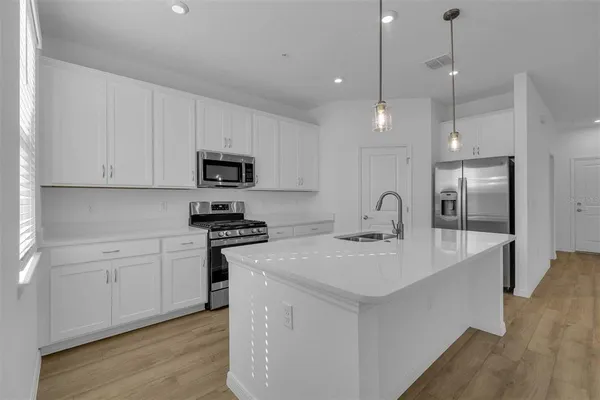 a kitchen with stainless steel appliances granite countertop a sink a stove top oven and refrigerator