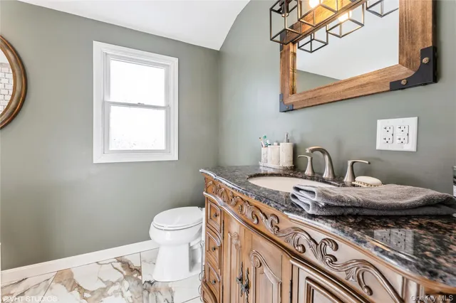 a bathroom with a granite countertop sink a toilet and a mirror