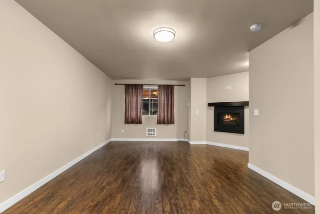 a view of an empty room with wooden floor and a fireplace