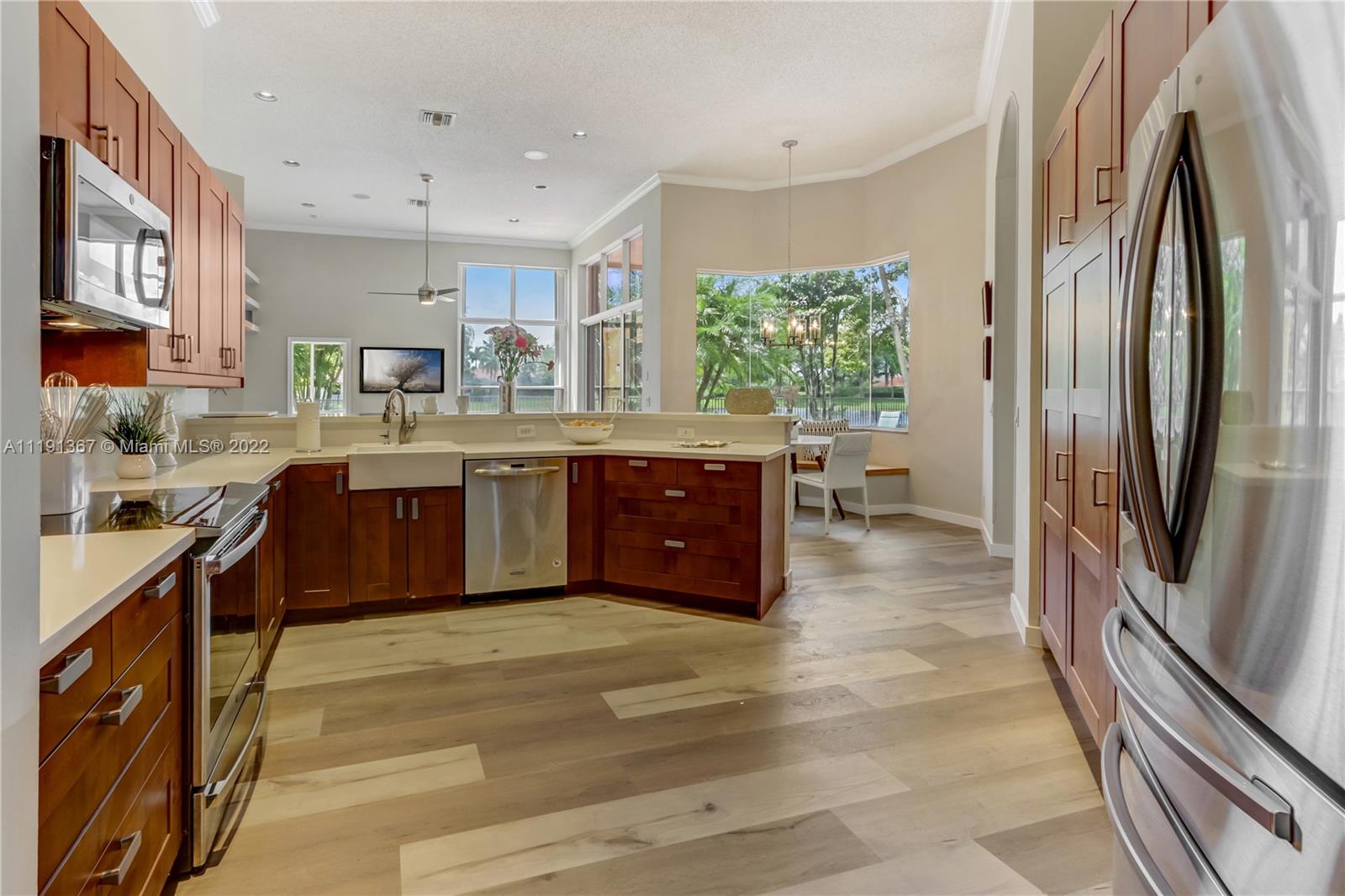 300 Mallard Road Weston, FL 33327 - Photo 24 of 46 a kitchen with stainless steel appliances granite countertop a refrigerator a sink dishwasher a stove and a dining table with wooden floor